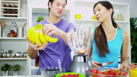 Pareja-joven-étnica-con-jugo-de-fruta-orgánica-de-blender