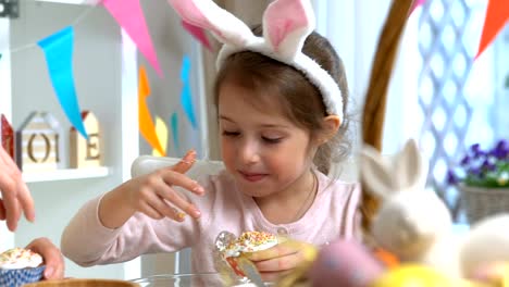 Young-mother-and-her-daughter-wearing-Bunny-ears-cooking-Easter-cupcakes