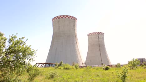 Two-cooling-towers-in-a-field-in-the-bright-sun.