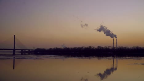 The-smoky-plant-on-the-background-of-the-river-and-the-setting-sun