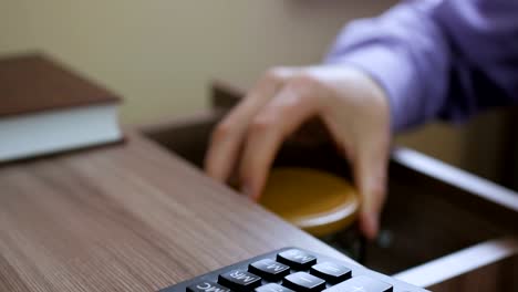 Caucasian-male-putting-a-glass-jar-put-in-a-drawer--table-with-his-savings-for-future-education