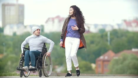 Hombre-discapacitado-en-silla-de-ruedas-caminar-juntos-a-su-novia-en-el-muelle