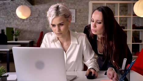 Young-woman-flirting-with-her-female-colleague-in-modern-office,-woman-annoyed-by-harassment-from-lesbian