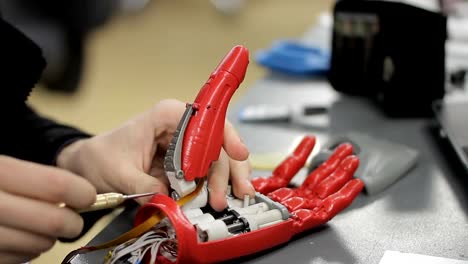 Close-up-of-young-man-assembling-bionic-hand-at-his-work-place