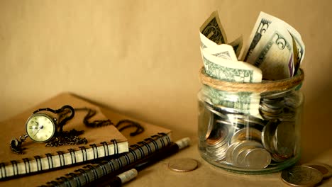 Books-with-glass-penny-jar-filled-with-coins-and-banknotes.-Tuition-or-education-financing-concept.-Scholarship-money.