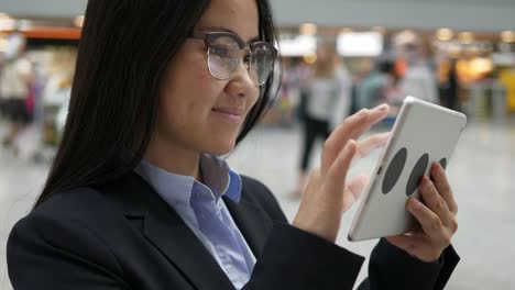 Asiatische-Geschäftsfrau-arbeiten-an-digital-Tablette-am-Flughafen