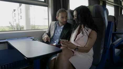 Viajeros-de-negocios-hablando-y-usando-Tablet-PC-y-smartphone-en-el-tren-entretenido-durante-el-viaje