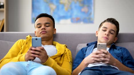 Afroamerikanische-und-kaukasische-Teenager-scrollen-Smartphones-und-haben-Freizeit