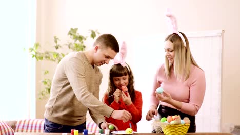 wife-with-husband-and-daughter-decorate-eggs-on-a-traditional-holiday.