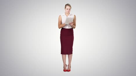 Attractive-businesswoman-using-a-digital-tablet-while-standing-on-gradient-background