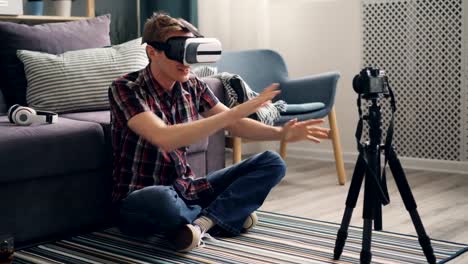 young-man-blogger-is-recording-video-about-virtual-reality-glasses-sitting-on-floor-at-home