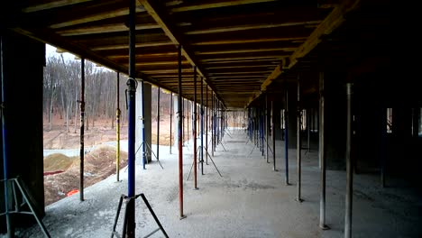 Movement-of-the-camera-between-the-building-supports-that-support-concrete-structures.-Unfinished-floor-on-the-construction-site