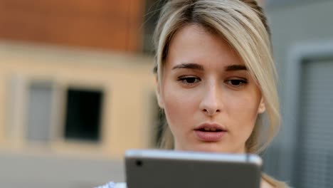 Close-up-portrait-of-young-girl-using-tablet-computer-outside.-Girl-doing-online-shopping-on-tablet-pc