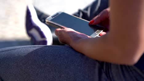 Tiro-recortado-de-la-joven-deportista-usando-el-teléfono-inteligente