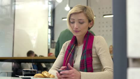 Mujer-en-Cafe-bebiendo-café-y-usando-el-teléfono-móvil