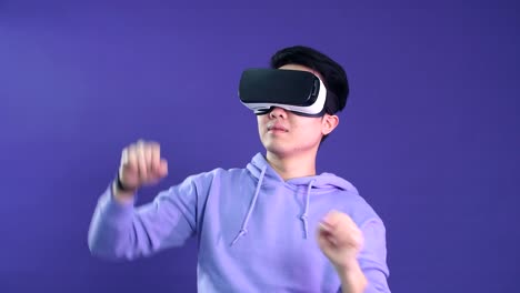 Asiatischer-junger-Mann,-der-Virtual-Reality-Headset-verwendet,-isoliert-über-violetten-Hintergrund