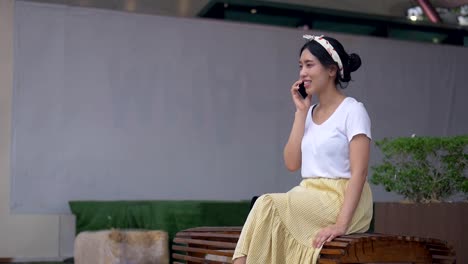 Portrait-young-asian-woman-sitting-chair-talking-on-phone-smiling-and-happiness.-Beautiful-young-business-lifestyle-using-technology.