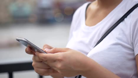 Junge-asiatische-Frau-mit-Smartphone-im-Freien-öffentlichen-Park.-Slow-Motion-hautnah.-Suche-im-Internet,-Online-Technologie.