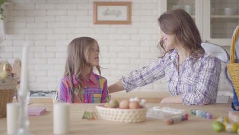 Junge-Mutter-und-ihre-vorangeklagte-Tochter-im-Gespräch-auf-der-Küche.