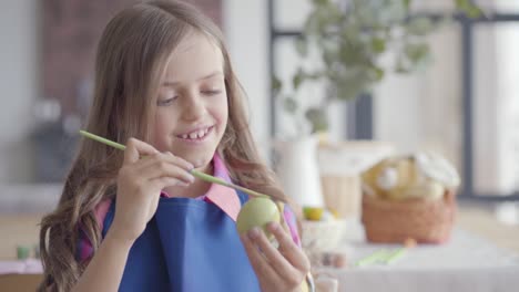 Portrait-of-cute-girl-painting-Easter-egg.