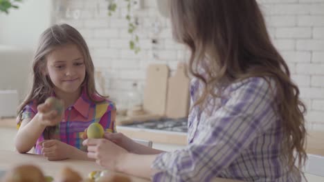 Portrait-mother-and-cute-daughter-sitting-at-the-Easter-table.