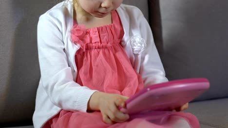 Female-kid-playing-toy-tablet-sitting-sofa,-childhood-leisure,-educational-toy