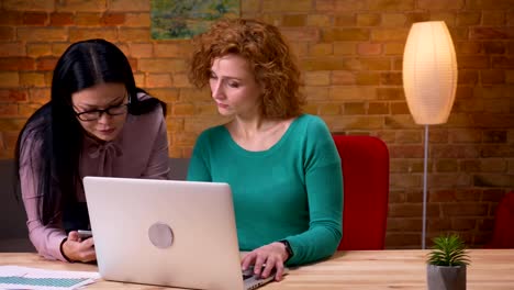 Closeup-shoot-of-adult-businesswoman-typing-on-the-laptop-indoors-in-the-office.-Female-employee-siscussing-with-her-data-on-the-tablet