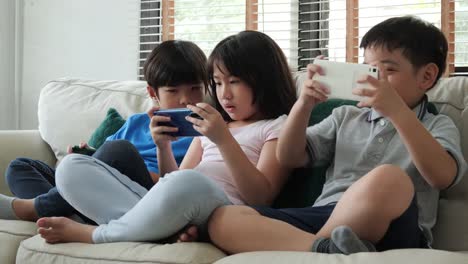 Group-of-children-friend-using-smartphone-to-play-game-together-at-home.-Children-playing-game-with-happy-emotion.