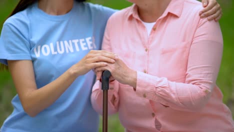 Sozialfreiwilliger-streichelt-alte-Patientin-Hand-auf-Gehstock,-Hospizhilfe