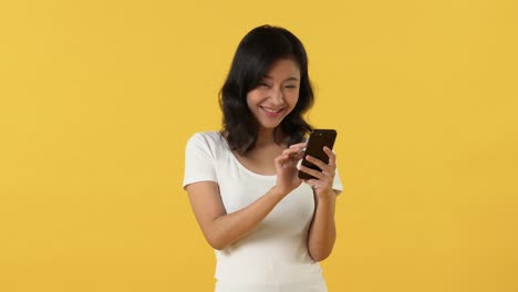 Excited-Asian-woman-reading-text-messages-on-cellphone