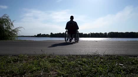 Un-hombre-en-silla-de-ruedas-camina-en-el-paseo-marítimo