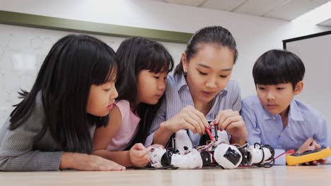 Gruppe-von-Schülern-und-Lehrern-in-der-Roboterklasse.-Berater-in-der-Studentin-über-ihr-Roboterprojekt-erklären.