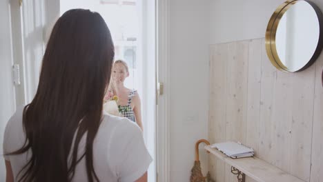 Woman-Opening-Front-Door-To-Gay-Partner-At-Home-Who-Gives-Her-Bunch-Of-Flowers