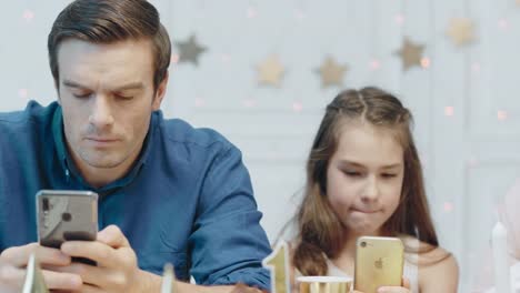 Portrait-of-concentrated-family-watching-mobile-phones-in-living-room.