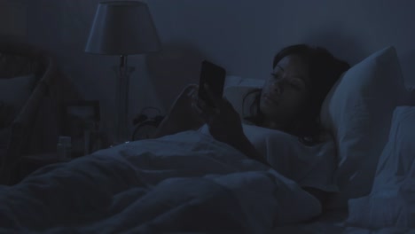 Mujer-usando-el-teléfono-en-la-cama-por-la-noche