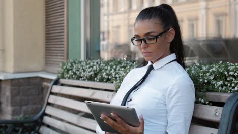 Woman-Reading-Tablet-Device.-A-young-Spanish-adult-female-latina-online-shopping-booking-outdoor-on-street,-airport-terminal