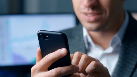 Close-up-of-a-successful-businessman-in-a-suit-is-using-a-smartphone-in-the-office-at-the-workplace.-Man-uses-the-application-on-a-mobile-phone,-office-on-the-background