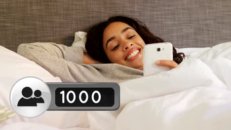 Woman-lying-in-bed-smiling-while-texting-on-her-phone-4k