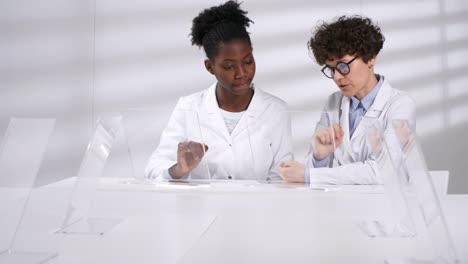 Two-Smiling-Female-Scientists-Discussing-Simulations-on-Futuristic-AR-Devices