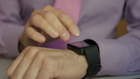 Man-using-his-smartwatch-app.-Closeup.-Businessman-using-trendy-smart-watches-mobile-application-on-touch-screen.-Guy-using-her-smartwatch-touch-screen-wearable-technology-device.-Close-Up.