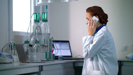 Woman-scientist-talking-on-phone-in-laboratory.-Scientist-in-lab