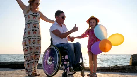 happy-Rest-near-sea,-invalid-with-wife-and-daughter-have-a-good-time-with-colorful-air-balloons,-family-with-child