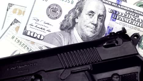 Cash-one-hundred-dollar-bills-under-the-gun,-rotating-background