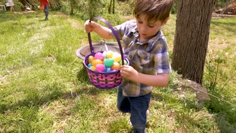 Young-male-child-standing-up-holding-a-basket-of-Easter-eggs-in-slow-motion