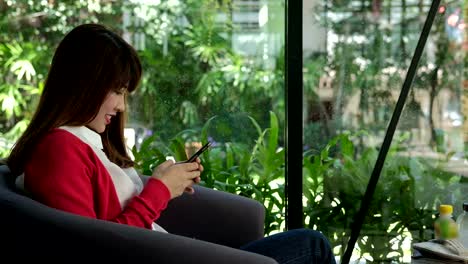 young-woman-wearing-red-cardigan-using-smartphone-for-social-networking.-girl-typing-text-message-on-application-in-mobile-phone.-technology,-communication,-people,-lifestyle-concept