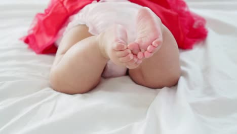 Baby-girl-lying-on-her-stomach-and-swing-her-legs-to-try-to-crawl-in-slow-motion-shot