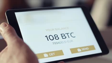 Man-prüft-das-Konto-auf-dem-Tablet.-Lager.-Überprüfung-der-Bitcoin-Saldo-auf-dem-Konto