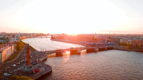 Vista-aérea-de-puesta-de-sol-sobre-el-río-Neva-y-columnas-rostrales-en-San-Petersburgo,-Rusia.-Ciudad-de-la-isla-Vasilievskiy-desde-arriba,-video,-históricos-edificios-drone-cinematográfico-del-norte-capital