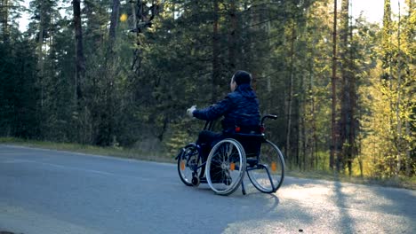 Training-wheelchair-is-getting-moved-along-the-road-by-a-disabled-man