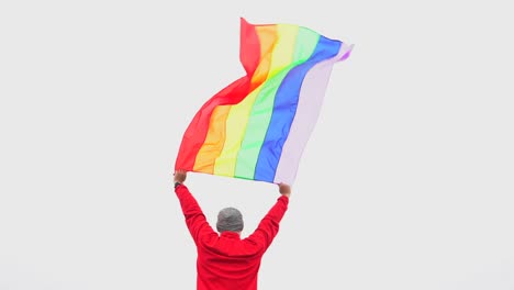 hombre-levantar-bandera-LGBTI-de-color-arco-iris-ondeando-en-duro-viento-en-el-mirador-de-alta-montaña